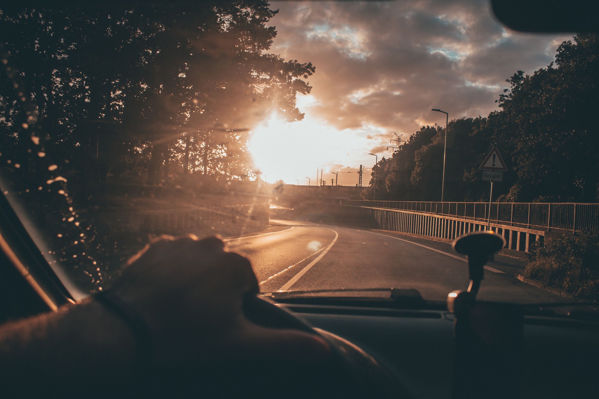Mano en el volante manejando hacia el sol