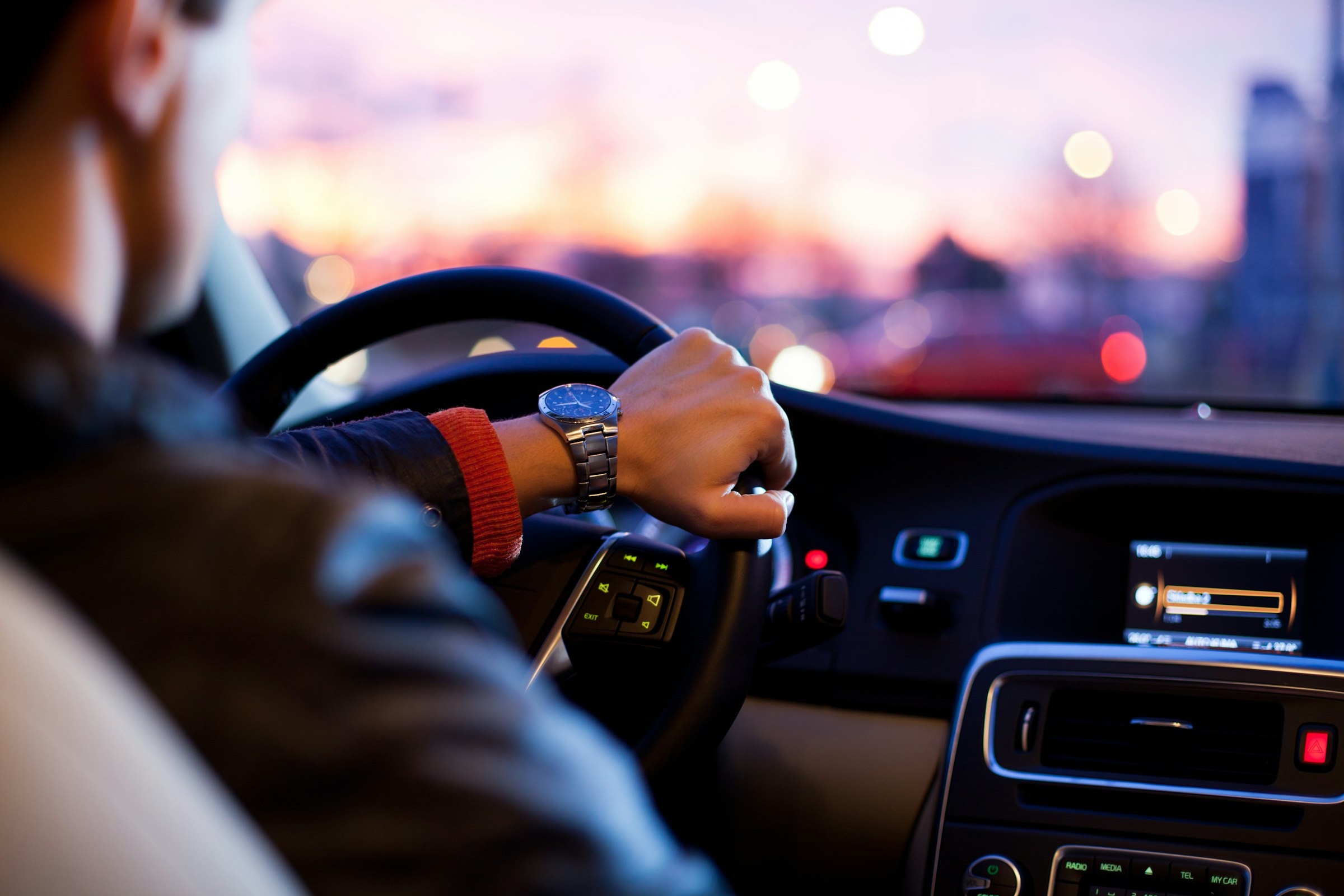 Conductor de espaldas al volante al atardecer